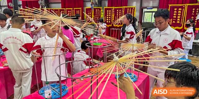 makes in short 90 characters   Shijingshan School students make traditional oil-paper umbrellas in a crafting class.