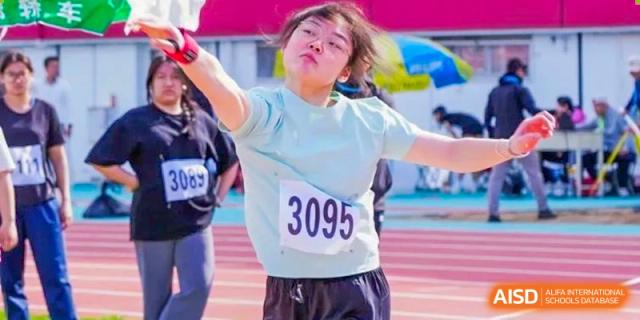 A female student from Shijingshan School of The High School Affiliated to Renmin University of China, wearing a light blue shirt, competes in a discus or shot put event.