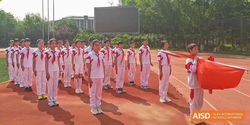 Students from Shijingshan School of The High School Affiliated to Renmin University of China in white tracksuits stand in a line on a track.