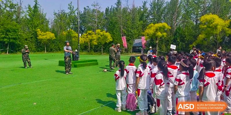 Students and teachers from Shijingshan School of The High School Affiliated to Renmin University of China participate in an outdoor activity in a park-like setting.