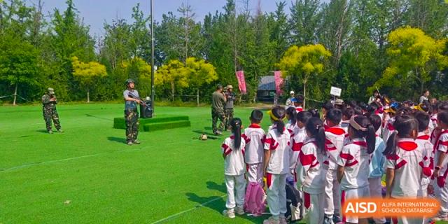 Students and teachers from Shijingshan School of The High School Affiliated to Renmin University of China participate in an outdoor activity in a park-like setting.