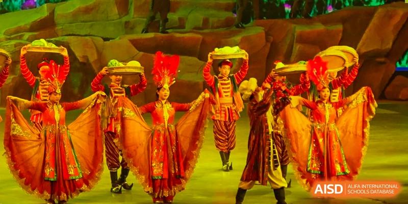 A stage performance with dancers in colorful traditional costumes from Shijingshan School of The High School Affiliated to Renmin University of China.