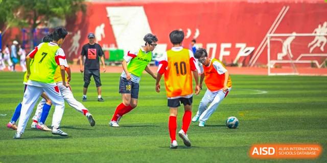 Students from Shijingshan School of The High School Affiliated to Renmin University of China play soccer on a green field.