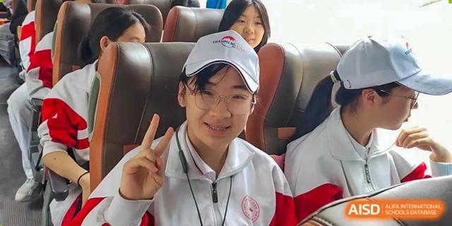 A student from Shijingshan School of The High School Affiliated to Renmin University of China smiles and makes a peace sign on a bus.