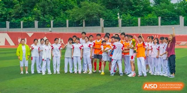 A group of students from Shijingshan School of The High School Affiliated to Renmin University of China stands together for a photo in front of a building.