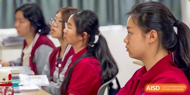 Close-up of three students in school uniforms listening intently during a classroom session. Beanstalk International Bilingual School (BIBS) - Chengdu