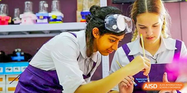 A student wearing safety goggles while focused on a detailed art or science project in class. Beanstalk International Bilingual School (BIBS) - Chengdu