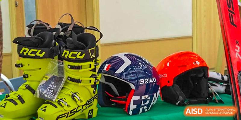 Professional ski gear including a yellow Fischer boot and a Briko helmet displayed on a green surface. Beanstalk International Bilingual School (BIBS) - Chengdu