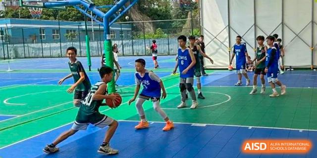 Students in jerseys playing a competitive basketball game on a vibrant blue and green outdoor court. Beanstalk International Bilingual School (BIBS) - Chengdu