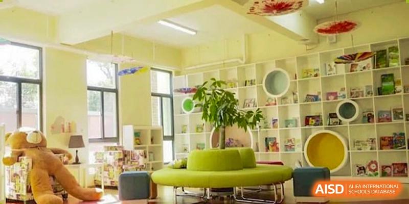 A bright, modern school library or common area featuring circular green seating and built-in shelving. Beanstalk International Bilingual School (BIBS) - Chengdu