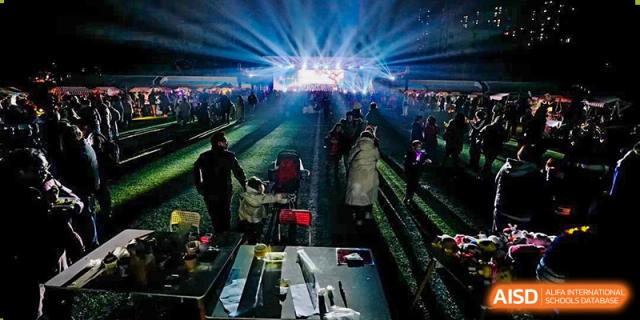 An evening outdoor event on the school grounds with bright stage lights and a large crowd gathered. Beanstalk International Bilingual School (BIBS) - Chengdu