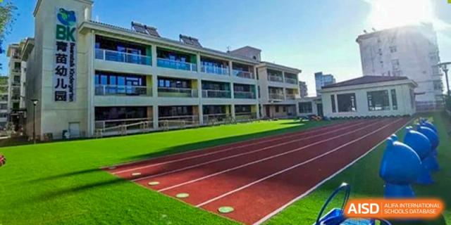 Modern multi-story school building overlooking a vibrant red running track and green sports field. Beanstalk International Bilingual School (BIBS) - Chengdu