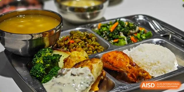A well-balanced school lunch tray containing rice, roasted chicken, sautéed greens, potatoes with gravy, and a side of vegetable soup at Beanstalk International Bilingual School (BIBS) - Chengdu.