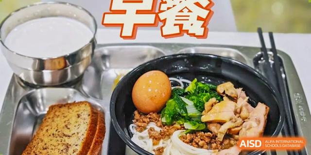 A healthy breakfast spread featuring a bowl of noodles topped with a hard-boiled egg, minced meat, and leafy greens, served with whole-grain bread at Beanstalk International Bilingual School (BIBS) - Chengdu.