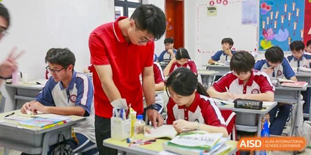A teacher wearing a red shirt helping a female student with her work in a classroom at The Experimental School Affiliated with Zhuhai No.1 High School.