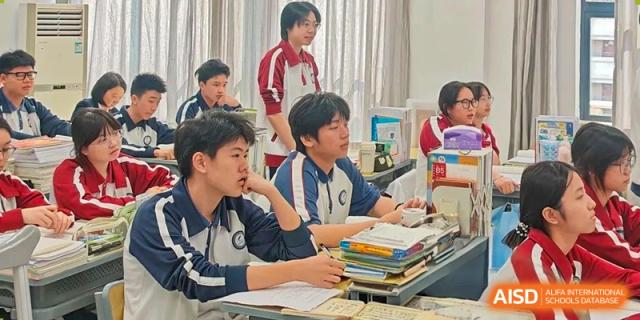 Students in blue and white uniforms studying and discussing material at their desks at The Experimental School Affiliated with Zhuhai No.1 High School.