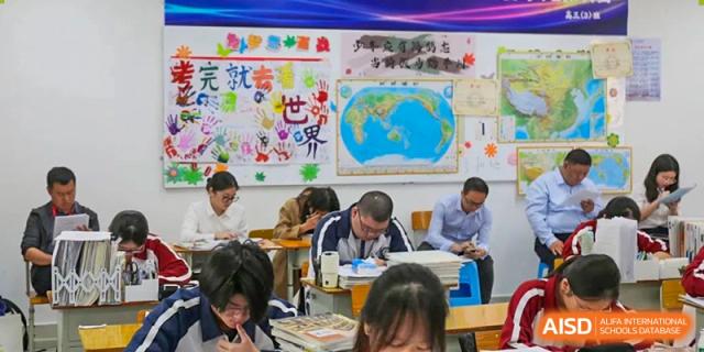 Students and a teacher studying or taking a test in a classroom with educational posters, including a world map, on the wall at The Experimental School Affiliated with Zhuhai No.1 High School.