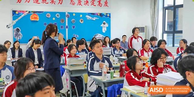 Students listening to a lesson in a classroom with motivational posters and blue walls at The Experimental School Affiliated with Zhuhai No.1 High School.