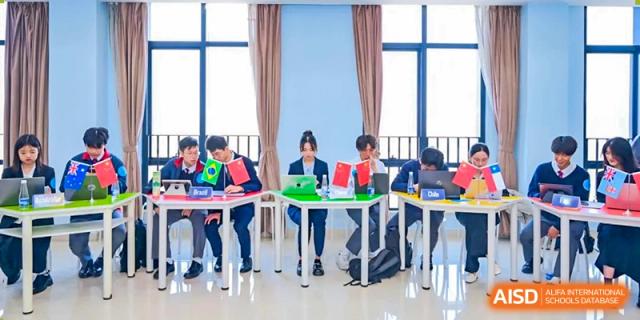 Students from The Experimental School Affiliated with Zhuhai No.1 High School participating in a small group discussion or competition at a long table.