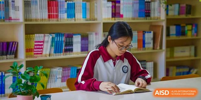A female student from The Experimental School Affiliated with Zhuhai No.1 High School studying a book while sitting in the school library.