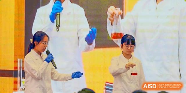 A student or teacher from The Experimental School Affiliated with Zhuhai No.1 High School conducting a chemistry experiment, holding a flask with a colorful liquid.