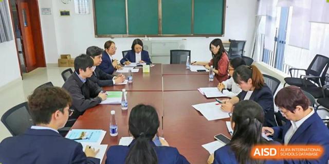 A group of teachers and administrators from The Experimental School Affiliated with Zhuhai No.1 High School having a professional discussion around a conference table.