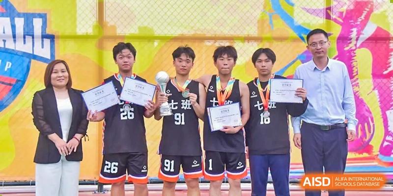 Winning student basketball players from The Experimental School Affiliated with Zhuhai No.1 High School posing with a trophy and medals after a competition.