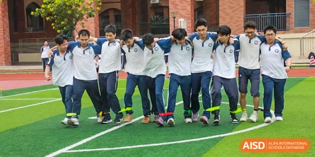 Students from The Experimental School Affiliated with Zhuhai No.1 High School participating in a teamwork field game, with their legs tied together.