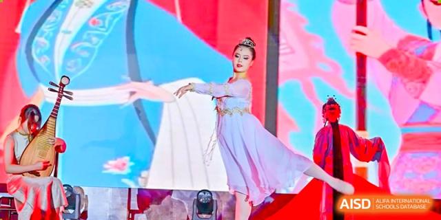 A student from The Experimental School Affiliated with Zhuhai No.1 High School performing a traditional or folk dance on stage in a light purple dress.