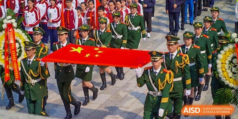 Military personnel carrying a large Chinese national flag in a procession, likely at an event for The Experimental School Affiliated with Zhuhai No.1 High School.