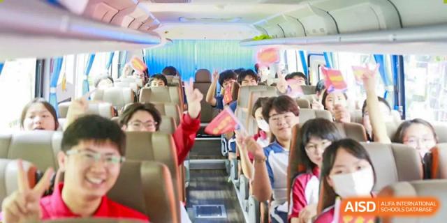 Excited students from The Experimental School Affiliated with Zhuhai No.1 High School waving and smiling while riding a bus.