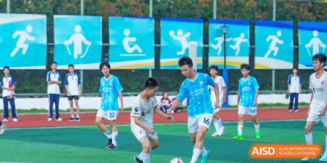 Students from The Experimental School Affiliated with Zhuhai No.1 High School competing in a soccer match on a turf field.