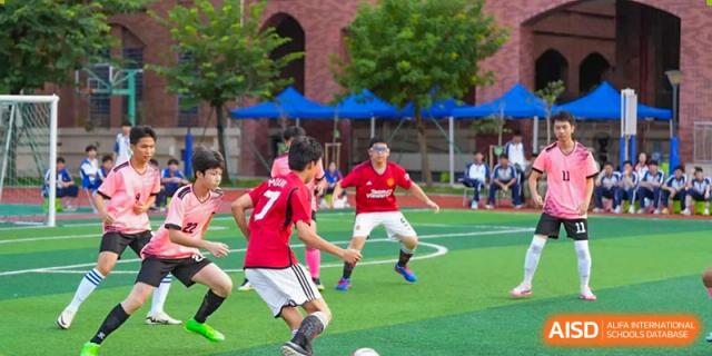 A player in a red jersey from The Experimental School Affiliated with Zhuhai No.1 High School preparing to kick the ball during a soccer match.