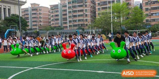 Students from The Experimental School Affiliated with Zhuhai No.1 High School participating in a fun outdoor group relay race or team-building activity.