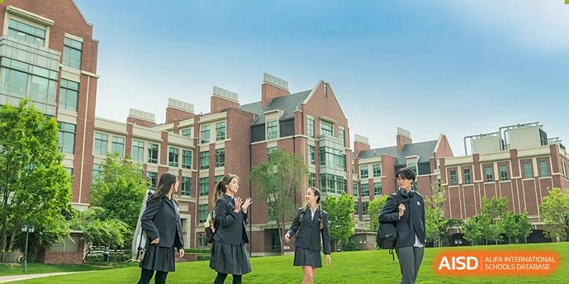 Beijing Keystone Academy students in their uniforms standing together on the campus with a school building in the background.