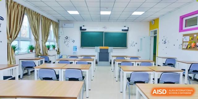 An empty classroom with desks and a blackboard at Beijing Zhongguancun Foreign Language School.