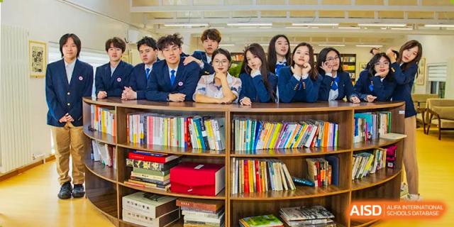A group of Beijing Zhongguancun Foreign Language School students posing for a photo in a library.