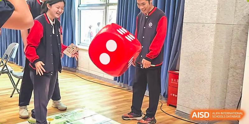 A photo showing two people holding a giant red die, at Beijing Zhongguancun Foreign Language School.