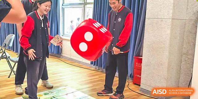 A photo showing two people holding a giant red die, at Beijing Zhongguancun Foreign Language School.