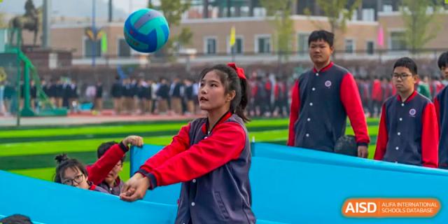 A female student from Beijing Zhongguancun Foreign Language School is preparing to hit a volleyball during a sports game.
