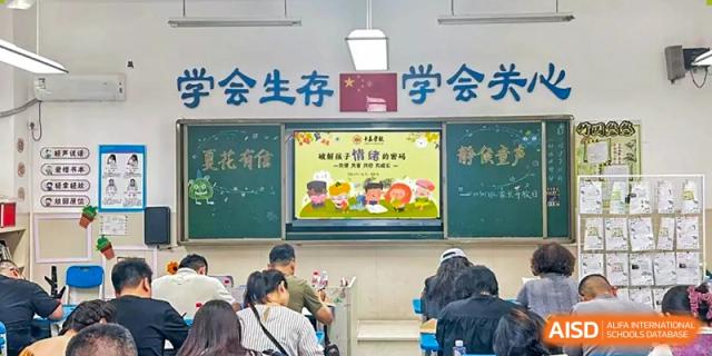 A teacher presenting academic content on a chalkboard and screen to students seated in a classroom at Changsha Lushan Zhongjia School.
