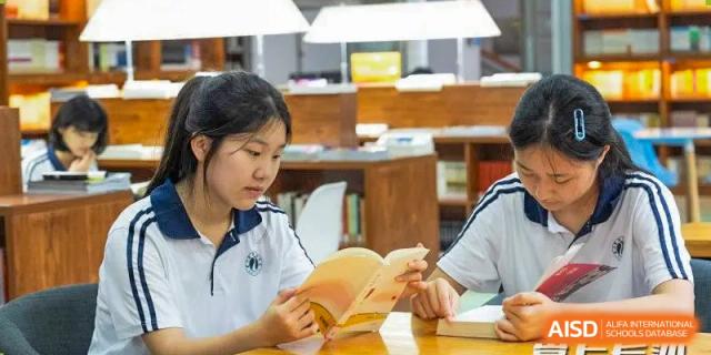 A focused female student from Changsha Lushan Zhongjia School reading a book in a library or study area.