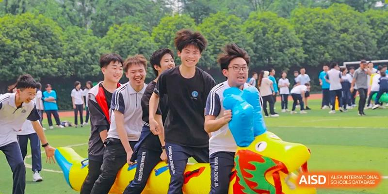 Male students of Changsha Lushan Zhongjia School laughing and running outside while participating in a fun field activity with colorful inflatable props.