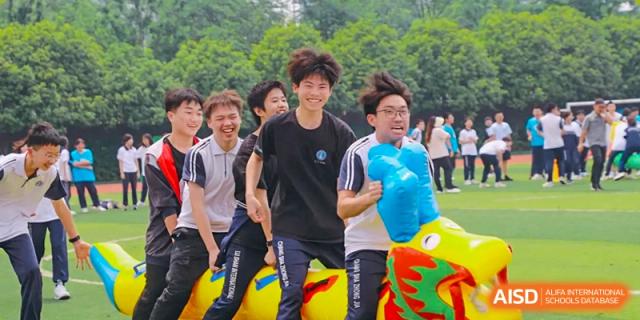 Male students of Changsha Lushan Zhongjia School laughing and running outside while participating in a fun field activity with colorful inflatable props.