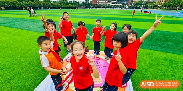 A joyful group of female students and a teacher from Changsha Lushan Zhongjia School wearing red shirts and celebrating during an event or activity.