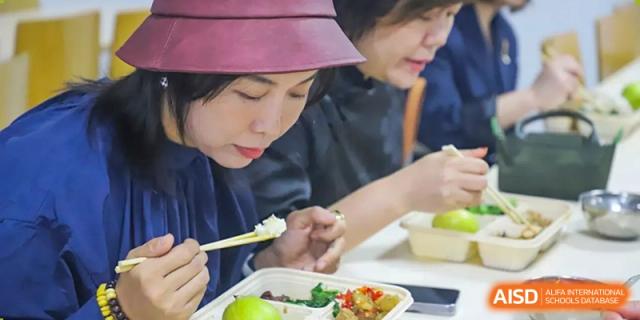 A close-up view of an adult and students from Changsha Lushan Zhongjia School enjoying their lunch together in the school dining area.