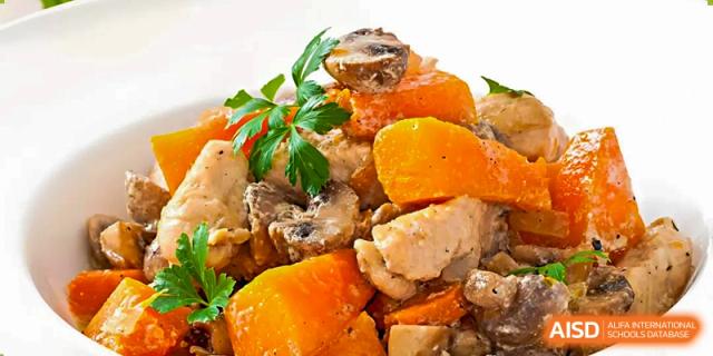 A close-up of a prepared meal served at Changsha Lushan Zhongjia School, featuring chunks of chicken, mushrooms, and large pieces of bright orange sweet potato or squash.