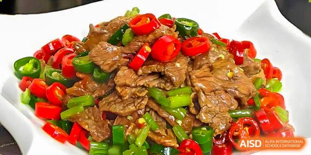 A close-up of a main course served at Changsha Lushan Zhongjia School, featuring stir-fried beef slices with green and red chili peppers.