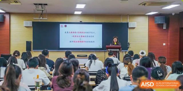 A female teacher stands at the front of a classroom presenting to students seated at desks, at Changshu Lunhua Foreign Language School.