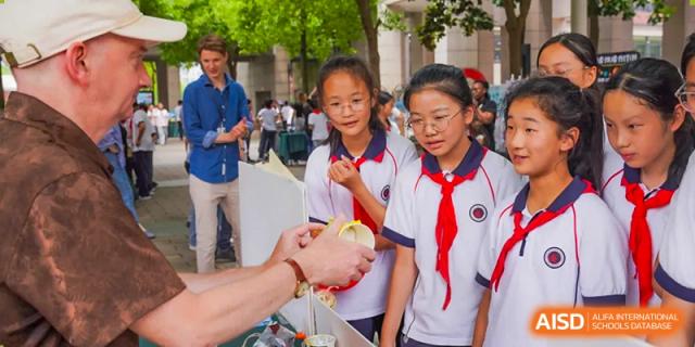 Two female students look at and hold a science project outside, at Changshu Lunhua Foreign Language School.